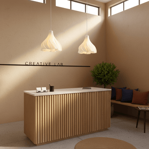 Two Marigold pendant lights hang above a wooden reception desk in a modern interior with a plant and seating.