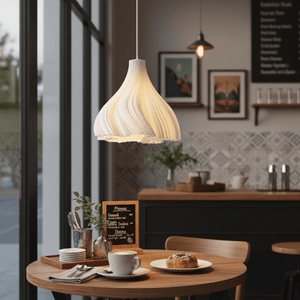 A white 3D printed pendant light hangs above a wooden table set with coffee and pastries.