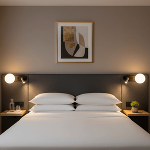 Bedroom with a double bed, two black and gold wall-mounted reading lights, and abstract art above the headboard.