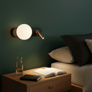 Stylish black and gold wall light mounted beside a bed, illuminating an open book on a nightstand.