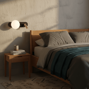 Stylish black and gold wall light mounted beside a bed, illuminating a cozy bedroom setting.