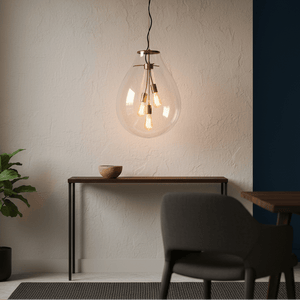 Matt brass pendant light with clear glass shade hanging above a wooden console table.