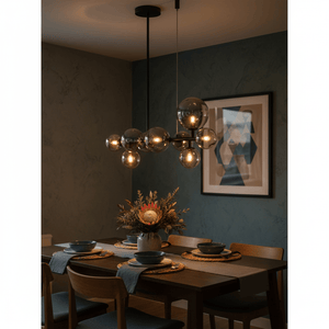 Stylish Nebula pendant light with smoke glass shades illuminating a dining table set with plates and a floral centerpiece.