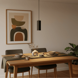 A sleek black pendant light hangs above a wooden dining table set with bowls and a vase, enhancing the modern decor.