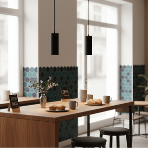 Stylish black pendant lights hang over a wooden table with pastries and coffee cups in a modern café setting.