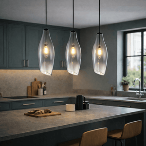 Three satin nickel pendant lights with smoke glass shades hang over a kitchen island, illuminating a cozy space.