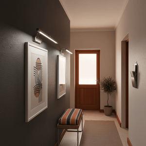 A hallway featuring two framed artworks illuminated by a sleek satin picture light, with a bench and potted plant.