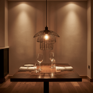 Stylish black pendant light above a wooden dining table set with glasses and plates.