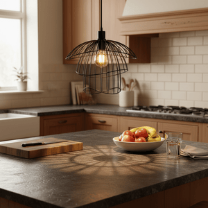 Stylish black pendant light casting shadows over a kitchen countertop with fruit and a glass.