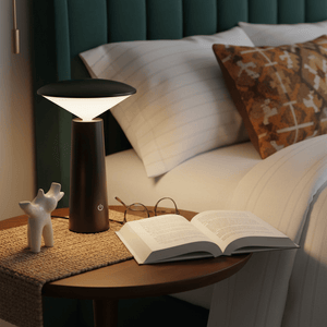 Rechargeable mini LED table lamp on a bedside table next to a book and glasses, creating a cozy reading atmosphere.