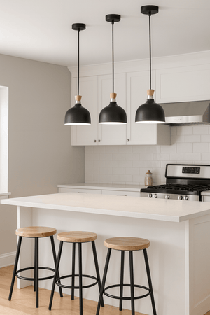 Three black metal and wood pendant lights hang above a kitchen island with wooden stools.