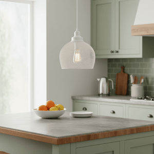 White metal pendant light hanging over a kitchen island with a bowl of fruit.