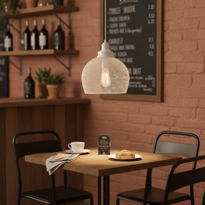 Metal pendant light in French white hanging above a wooden table set with coffee and a croissant.