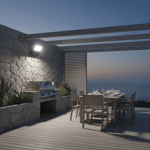 Coastal floodlight illuminating a patio dining area with a grill, surrounded by plants and a scenic view.