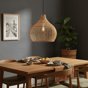 Haiti Bamboo Rattan Pendant light hanging above a wooden dining table set with bowls and a plant in the background.