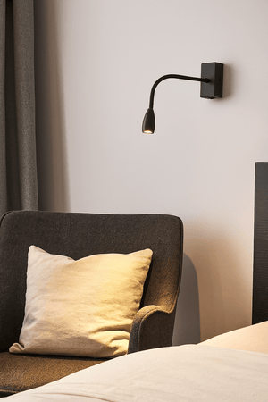 Modern wall lamp above a bed with a pillow