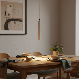 Minimalist white pendant light hanging above a wooden dining table set with bowls and a plant.