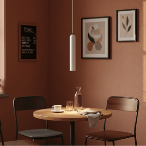 Minimalist white pendant light hanging over a wooden table set with drinks and tableware in a cozy dining area.