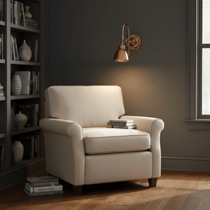 Antique brass wall lamp illuminating a cozy reading nook with an armchair and bookshelves.