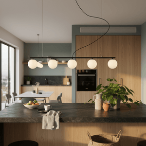 Linear 5-light pendant in black above a kitchen island with round glass shades, surrounded by modern decor.