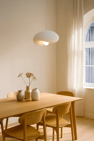 Ivory Drift 300 Pendant Light hanging above a wooden dining table with vases and dried flowers.