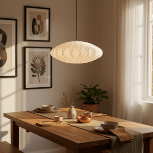 Silk Pendant Light hanging above a wooden dining table set with dishes and decor, casting soft light.