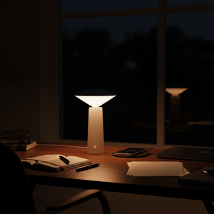 A modern white mini LED table lamp illuminating a desk with books and a smartphone.