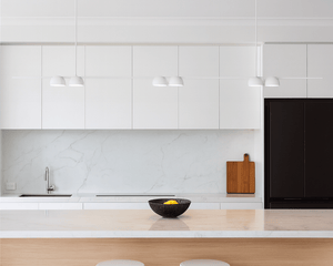 Modern kitchen with white cabinets, wooden island, and white stools.
