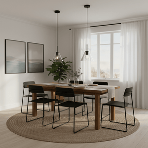 Stylish dining area featuring two black pendant lights above a wooden table with black chairs and a plant.