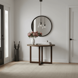 Stylish interior featuring a round wooden table with flowers, a mirror, and a black pendant light.