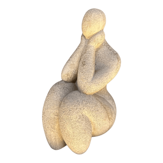 Textured beige abstract seated figurine shown alone on a green background