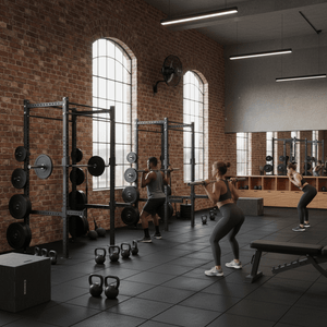 Black industrial wall fan mounted on brick wall above arched windows with weight racks and kettlebells