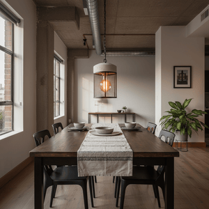 Cement and metal cage pendant light hanging over a wooden dining table set with plates and cutlery.