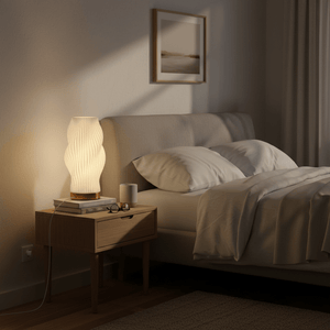 A modern 3D printed table lamp with a sculptural design on a bedside table, illuminating a cozy bedroom.