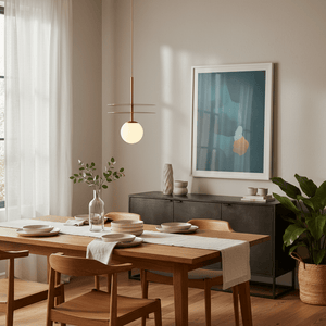 Catalina Duo Gold Pendant Light hanging above a wooden dining table set with plates and a vase.