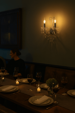 Elegant wall light with crystal embellishments illuminating a dining table setting.