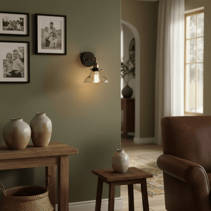 Antique brass wall light with adjustable arm illuminating a cozy indoor setting, featuring decorative vases and framed