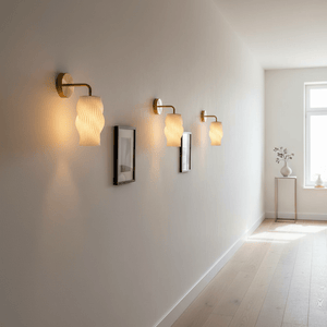 Three Dahlia wall lights mounted on a smooth wall, illuminating framed artwork and a side table.