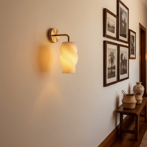 3D printed wall light with a sculpted shade illuminating a hallway, surrounded by framed photos and decor.