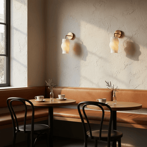 Two Dahlia 3D printed wall lights illuminate a cozy café corner with a wooden table and leather seating.