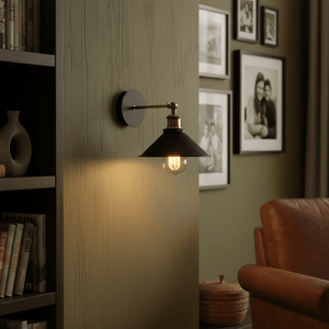 Rustic black wall light mounted on a textured green wall, illuminating a cozy reading nook.