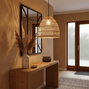 Woven rattan pendant light hanging above a wooden console table with decorative items and a mirror.