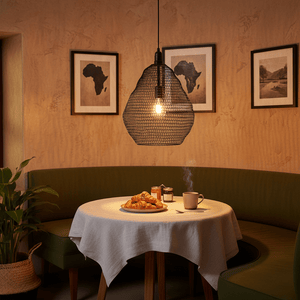 Phantom Black 500 Wire Mesh Pendant light hanging over a cozy dining table with croissants and coffee.