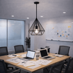 Geometric metal pendant light hanging over a modern office table with laptops and documents.