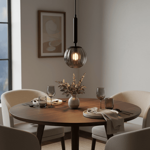 Black pendant light with ribbed glass globe and illuminated bulb hanging from a black cord