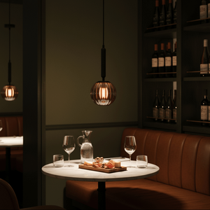 Black pendant light with smoked glass shade hanging over a round marble dining table.