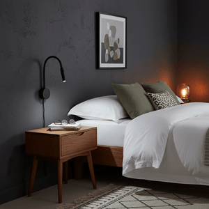 LED wall light mounted beside a bed, providing focused light for reading, with a stylish bedside table and decor.