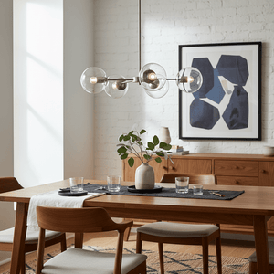 Satin chrome pendant light with clear glass shades above a wooden dining table, featuring a modern decor style.