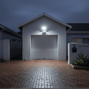 LED motion sensor floodlight illuminating a driveway and garage at night, enhancing visibility.