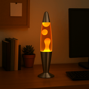 Red and yellow lava lamp with silver base on a wooden desk beside books and a computer monitor.